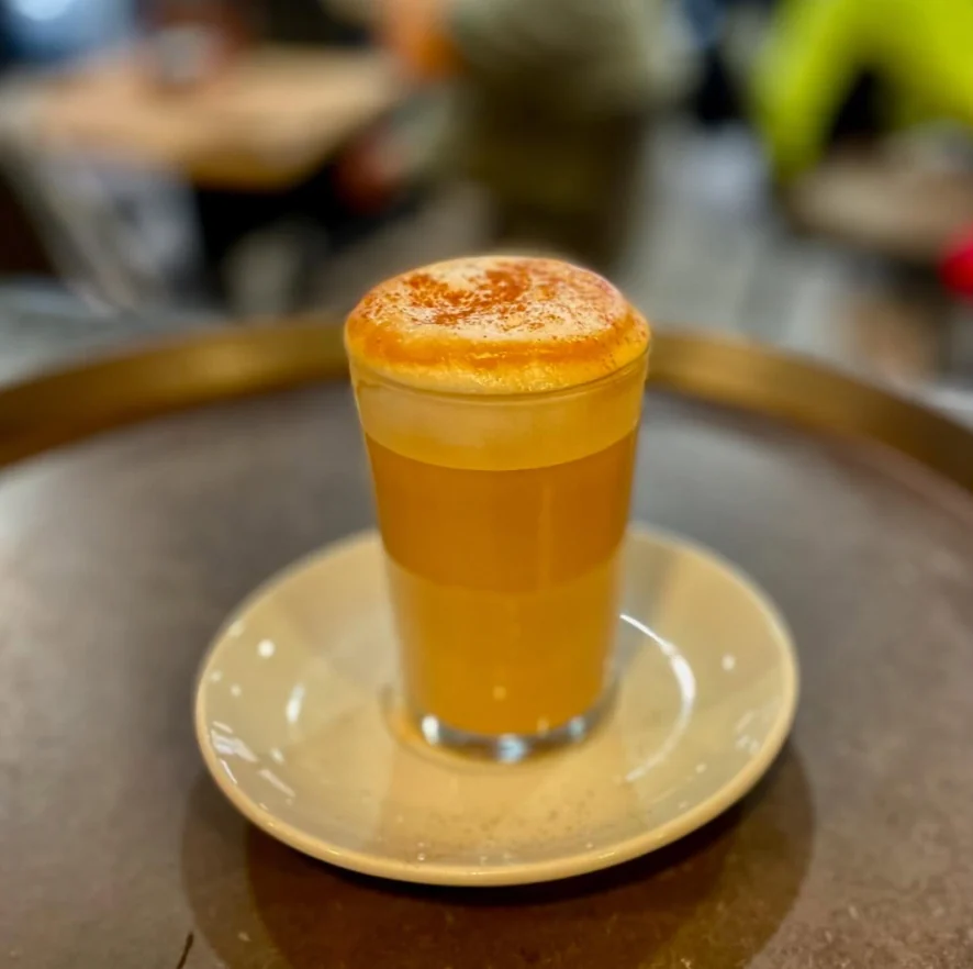 Café con leche en vaso con canela sobre un plato